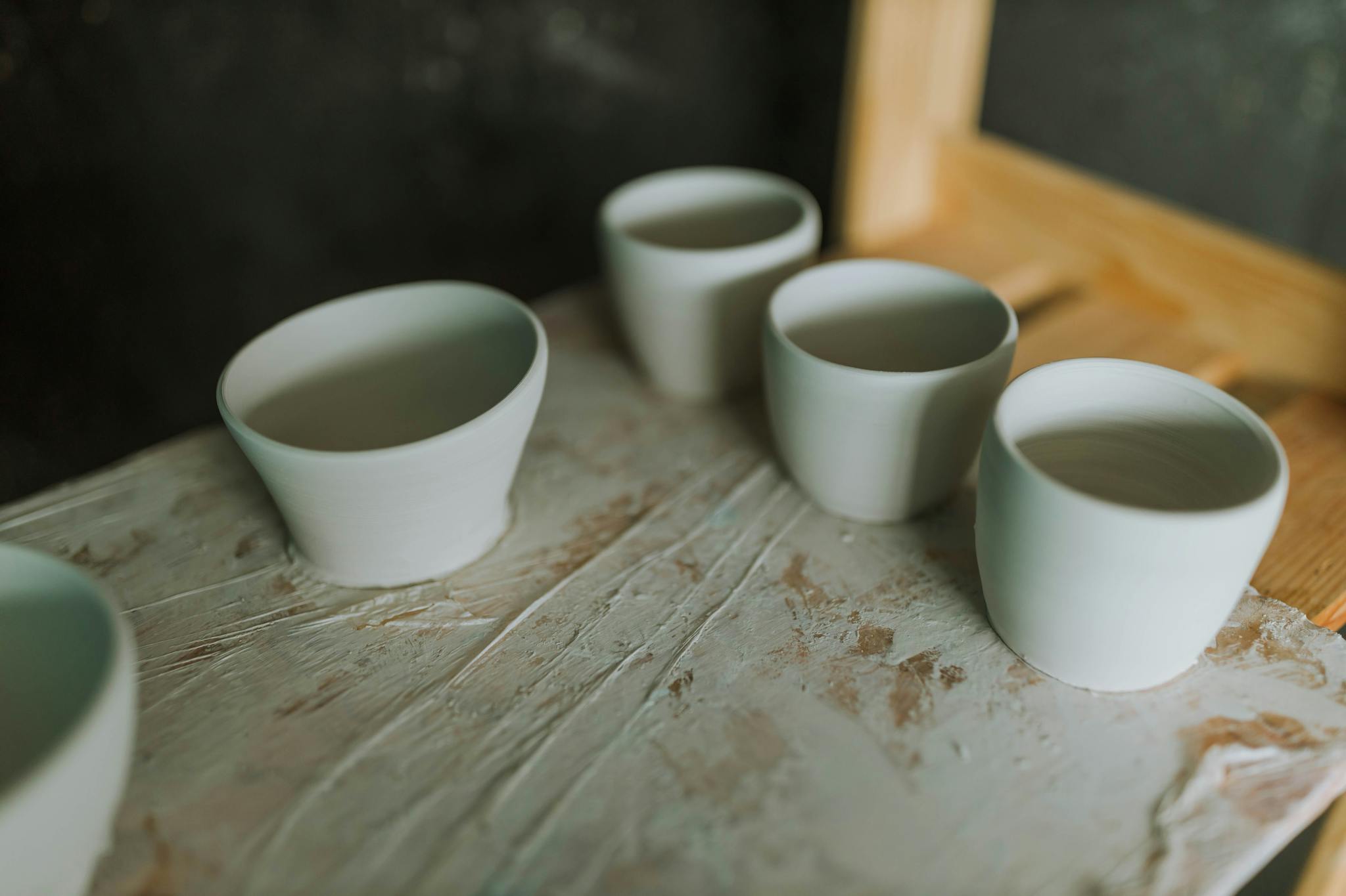 A close-up of minimalistic handcrafted ceramic cups on a rustic wooden surface.