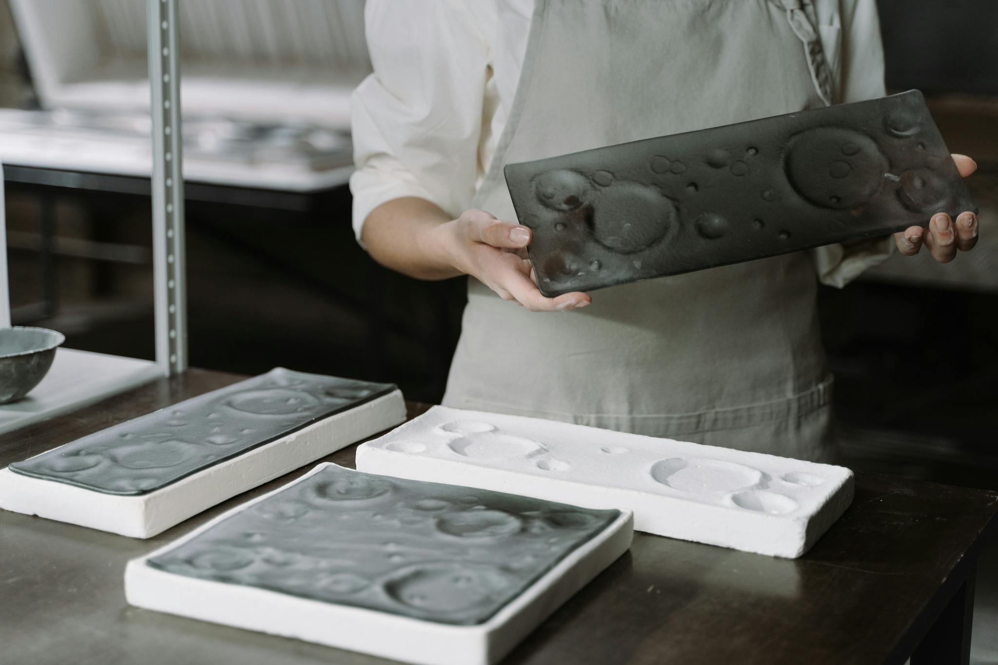 Artisan showcasing handcrafted ceramic plates in an artisanal workshop setting, highlighting craftsmanship.
