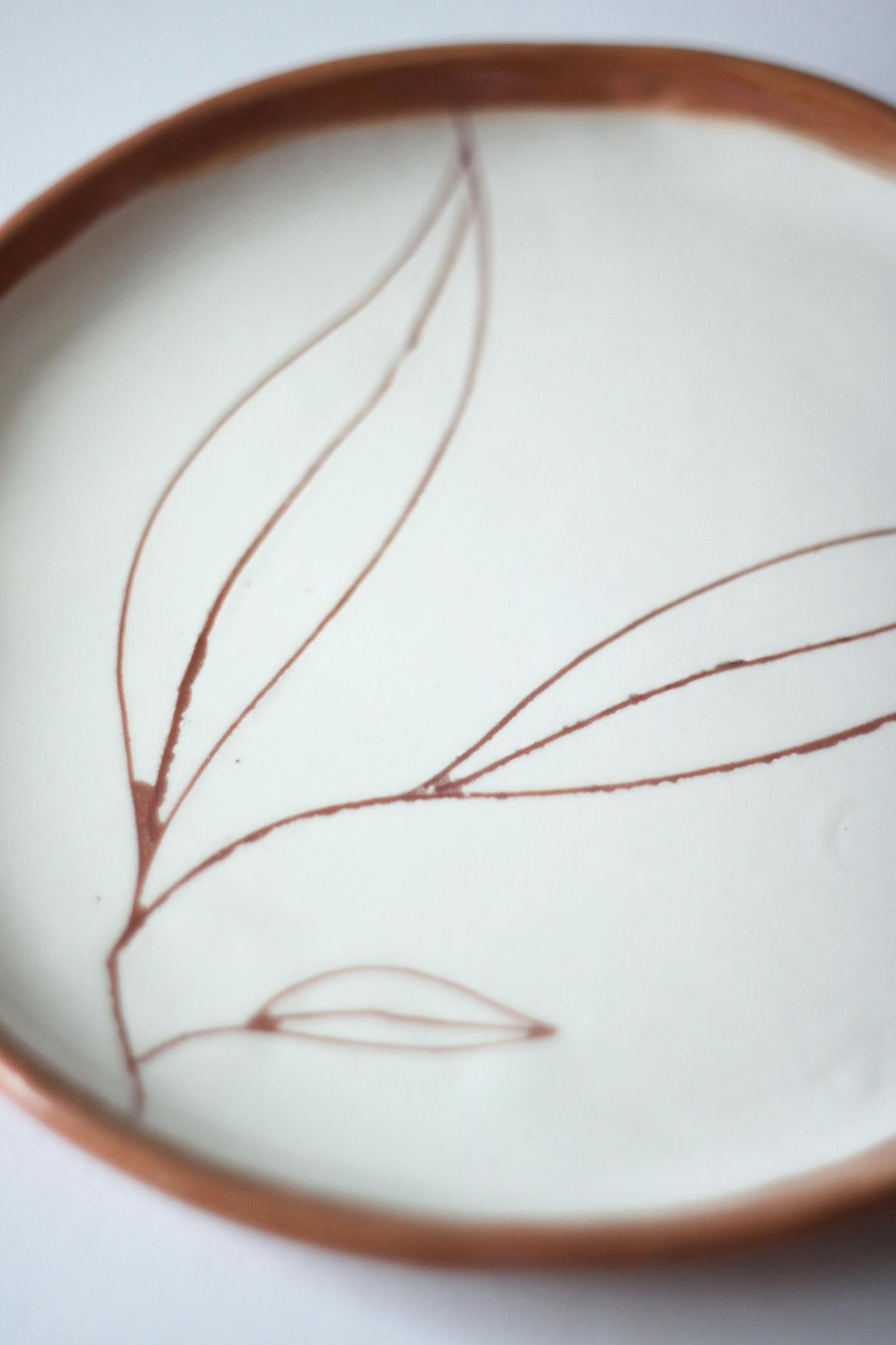 Close-up of a handmade ceramic plate with a minimalist leaf design.