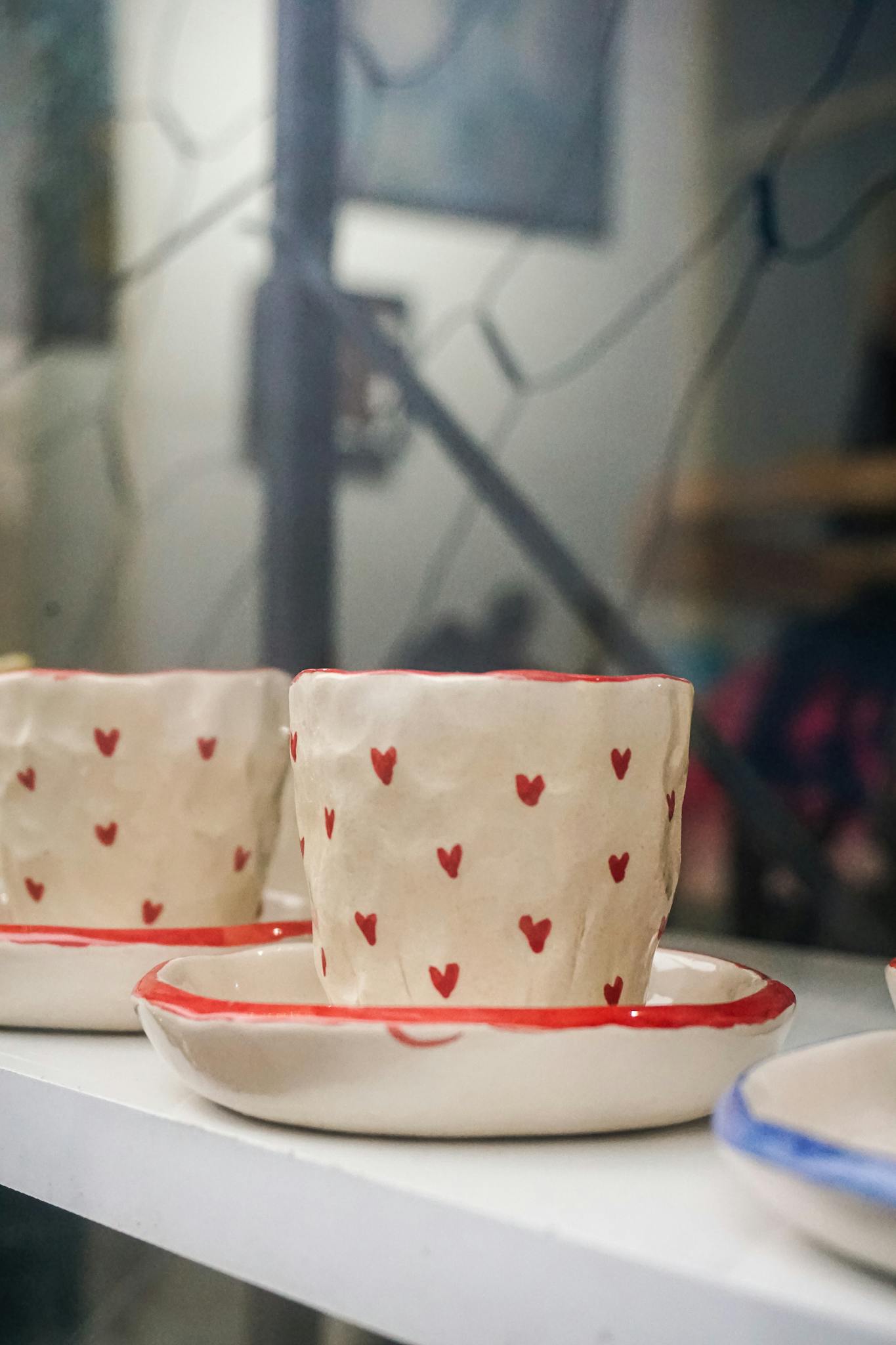 Close-up of handmade ceramic cups with heart patterns, perfect for gifting or decor.